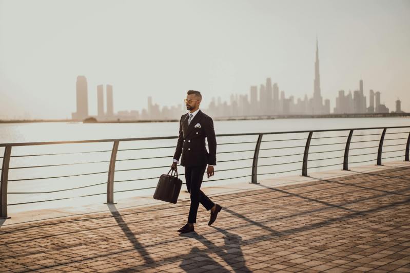 Busy business man walking by the water in a business suit with sunglasses dressed sharp