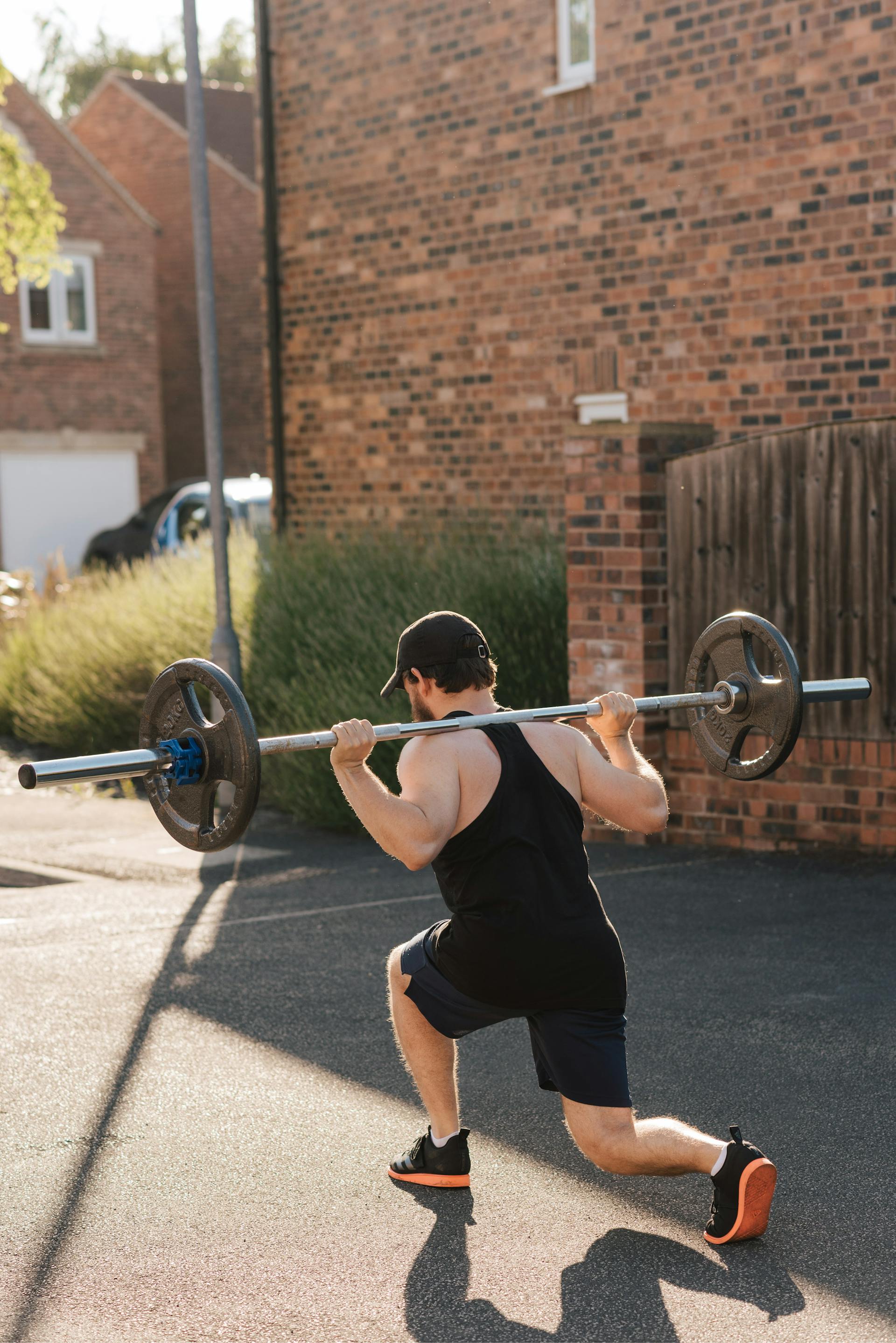 man doing barbell lunge outside brick wall