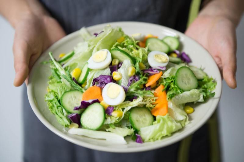 Person holding a bowl of salad